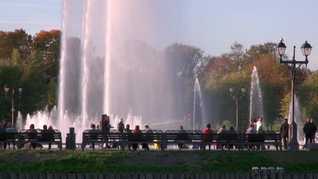 People in park on bench near fountains in summer in Moscow. Beautiful views of capital of Russia.