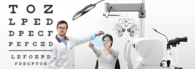 optometrist examining eyesight woman patient pointing chart at the hole on plexiglass in optician...