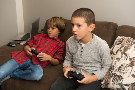 Two happy  young boy friends playing video games, holding remote controlers