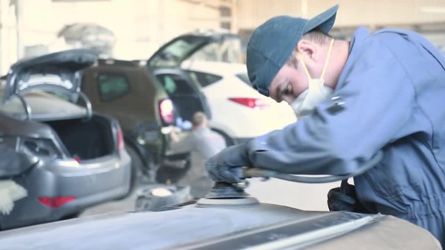 auto repairman grinding autobody bonnet