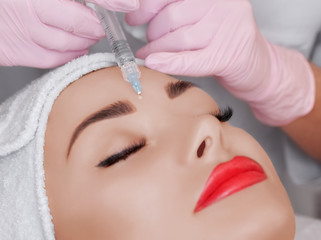 Obraz na płótnie Canvas The doctor cosmetologist makes the Rejuvenating facial injections procedure for tightening and smoothing wrinkles on the face skin of a beautiful, young woman in a beauty salon.Cosmetology skin care.