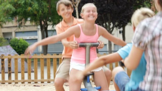 Children are teetering on the swing on the playground.