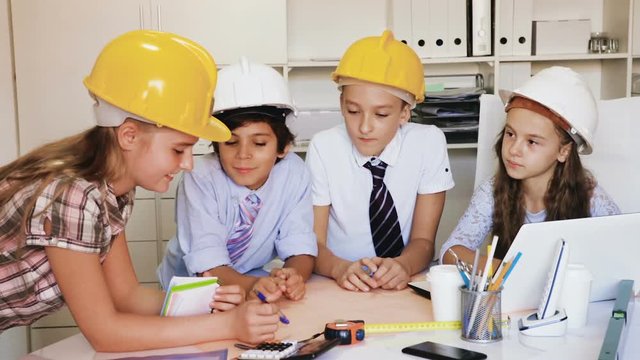 Group of children in helmet talking about building near laptop