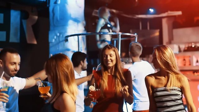 Group of smiling people clubbing in the night club with drinks