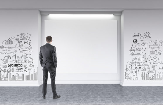 Rear view of a man looking at a wall business plan