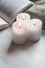 Obraz na płótnie Canvas Candles and book with cozy blanket