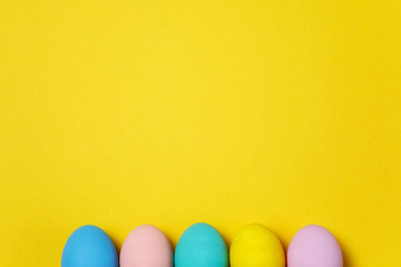 Row of five colorful pastel monophonic painted Easter eggs isolated on yellow background for card or postcard. Happy Easter concept. Copy space for advertisement. With place for text. Top view on eggs
