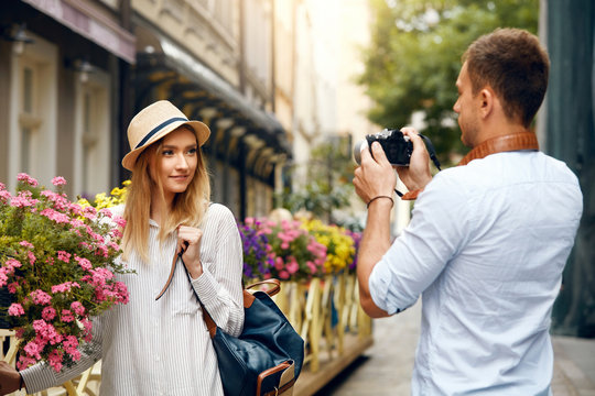Tourist Couple. Man With Camera Taking Photos Of Woman In Street