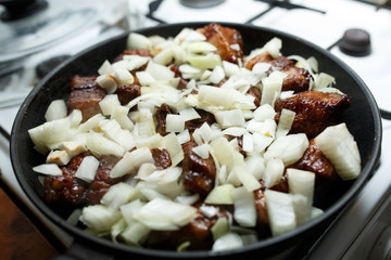 Pork ribs with onion fried in a pan.