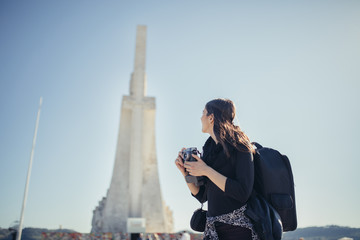 Trip to Portugal and Europe.Traveling to Lisbon.Female turist sitting on a square mosaic map in front of Monument of the Discoveries in Lisbon.Vacation pictures concept.Explore and travel.
