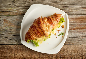 Croissant sandwich with cheese on wooden table