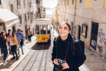 Young cheerful woman walking down the street of Lisbon.Amazed tourist visiting Europe off season during winter.Student in Portugal,Europe on a spring brake trip exploring big cities.Positive female