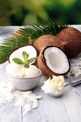 Bowl with balls of coconut ice cream and desiccated coconut on wooden table