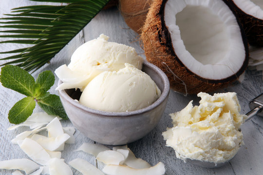 Bowl with balls of coconut ice cream and desiccated coconut on wooden table