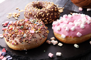 assorted donuts with chocolate frosted, pink glazed and sprinkles donuts.