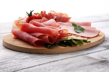 Food tray with delicious salami, pieces of sliced ham, sausage, tomatoes, salad and vegetable - Meat platter with selection