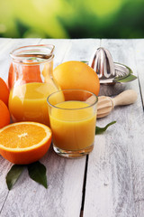 Glass of orange juice and slices of orange fruit on wooden background.
