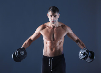 Handsome muscular man working out with dumbbells. Personal fitness instructor. Personal training.