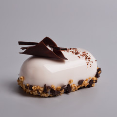 French mousse cake covered with white glaze. Luxury dessert decorated of chocolate composition with cream