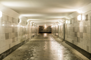 The underground passage is faced with gray granite and marble. People cross the road through the tunnel. The ladder is up.