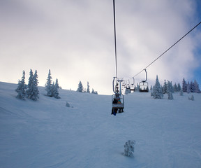 Fototapeta na wymiar Ski lift in winter snowy landscape in mountains on sky background