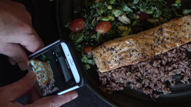 Food Photography with Mobile Phone Camera. Taking picture of Grilled Salmon Fillet with Wild Rice and Collar Greens