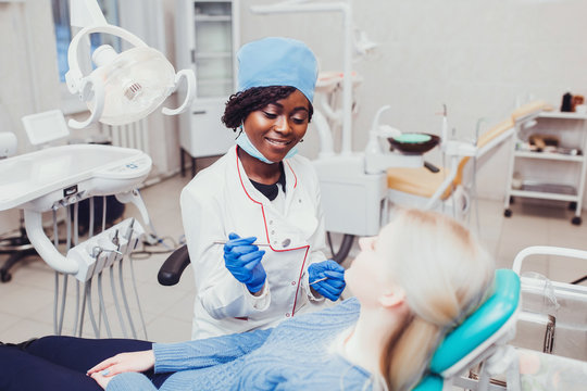 young black girl doctor dentist treats white girl's teeth
