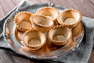 tartlets on silver vintage plate decorated with linen napkin on wooden table background

