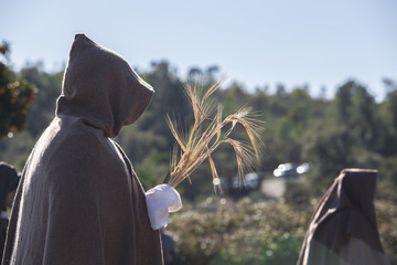 Hooded entourage members with wheat bundle offering