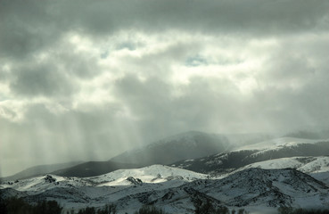 Fototapeta na wymiar View of snow covered hills with sun rays coming through the clouds, mountains, winter, snow
