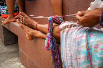 tanned legs of an old authentic Indonesian woman at work. The legs of an ordinary Asian woman hold the thread for knitting.