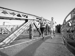 Fototapeta premium young couple jogging across the bridge in the city