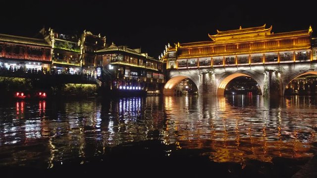 Boat sailing along the Tuojiang River in Fenghuang at night