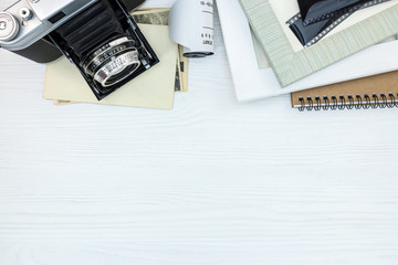 empty photo frames, old papers and vintage camera on white background flat lay