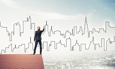 Man architect draw silhouette of modern city on blue sky. Mixed 