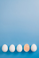 White eggs is laying in row, one of them is bisected and shows yolk.