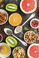 Ingredients of healthy dietary food breakfast pink grapefruit, orange, chia seeds, quinoa, green herbs, kiwi, wild rice, almonds, walnuts, hazelnuts on a gray background. The concept of natural