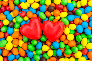 Obraz na płótnie Canvas Two red hearts on the background of sweet round candies. Top view.
