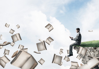 Man using smarphone and many books flying in air