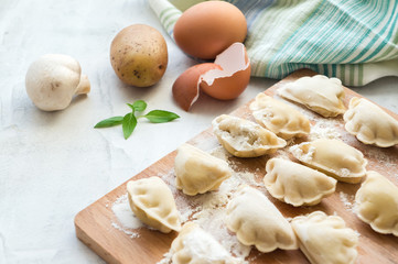 Cooking vareniki. Raw dumplings with potato and mushrooms. Concrete table. Side view. 