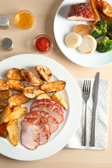 Plate with sliced honey baked ham and vegetables on table
