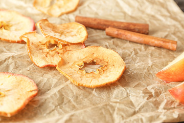 Tasty apple chips and cinnamon sticks on parchment