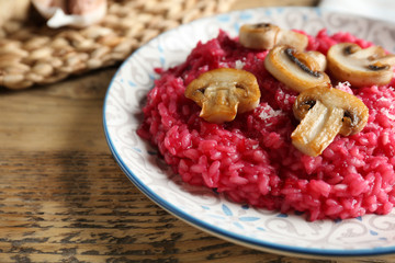 Plate of tasty beetroot risotto with mushrooms on table, closeup