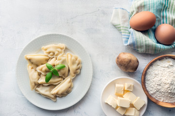 Traditional homemade food - dumplings (vareniki) with potato on concrete kitchen table. Top view.