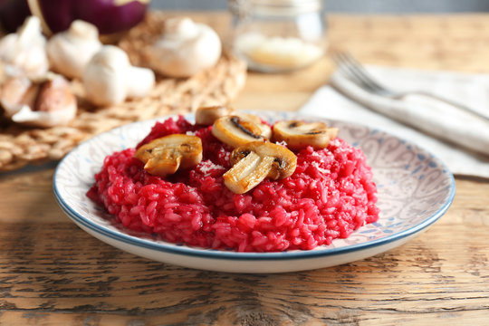 Plate of tasty beetroot risotto with mushrooms on table, closeup