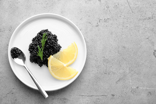 Plate with black caviar and slices of lemon on table