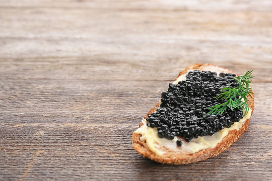 Bread with black caviar and butter on wooden table