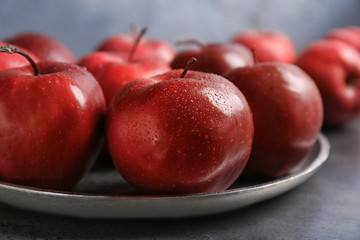 Plate with ripe red apples on table, closeup