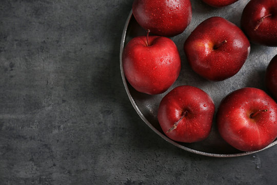 Plate with ripe red apples on grey table