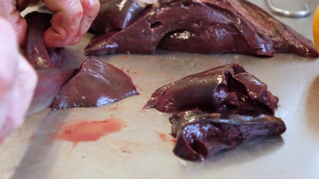 Butcher cuts liver on a steel table